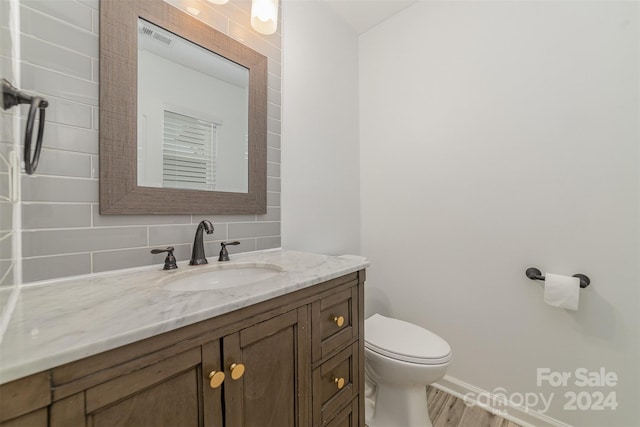 bathroom featuring hardwood / wood-style flooring, vanity, toilet, and tasteful backsplash