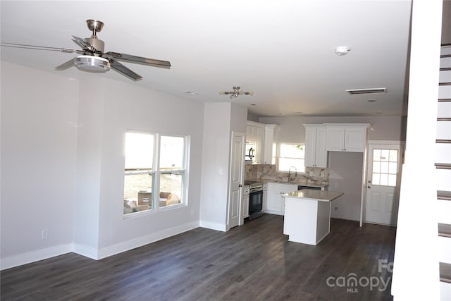 kitchen with dark wood-type flooring, backsplash, a center island, stainless steel range with electric cooktop, and white cabinetry