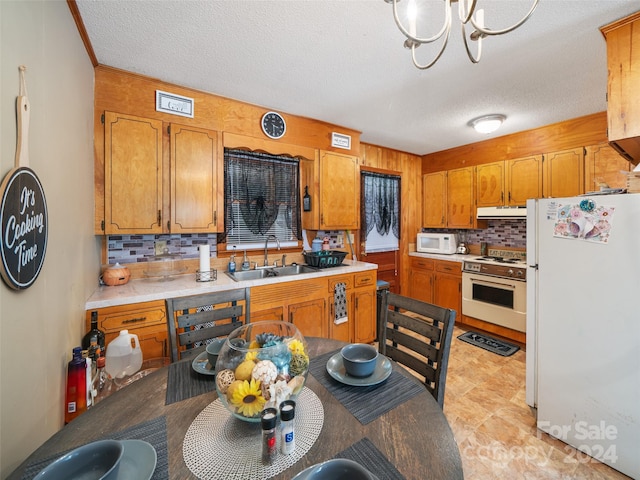 kitchen featuring a textured ceiling, sink, backsplash, and white appliances