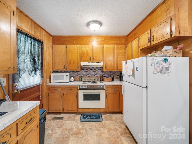 kitchen featuring decorative backsplash, a textured ceiling, and white appliances