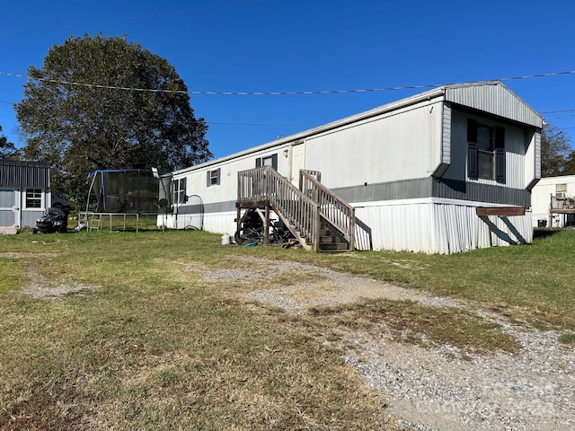 view of side of home featuring a trampoline and a lawn