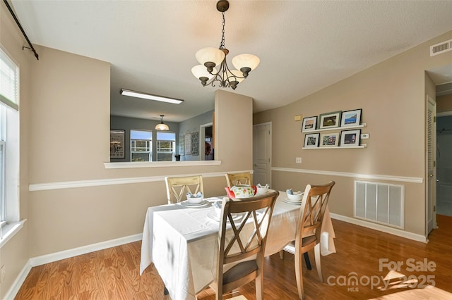 dining area featuring light wood finished floors, baseboards, visible vents, and an inviting chandelier