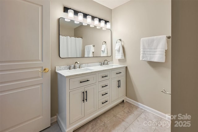 full bathroom with double vanity, a sink, and baseboards