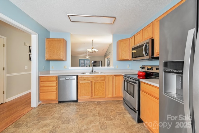 kitchen featuring stainless steel appliances, light countertops, an inviting chandelier, vaulted ceiling, and a sink