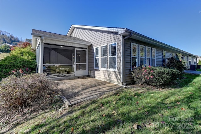 rear view of property with a sunroom, a patio, and a yard