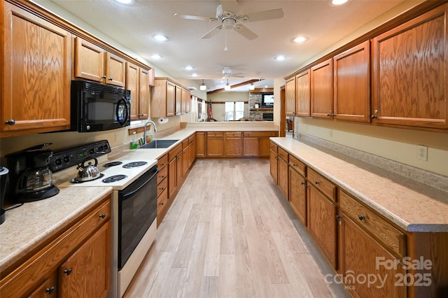 kitchen with white range with electric cooktop, brown cabinetry, a sink, light wood-type flooring, and black microwave