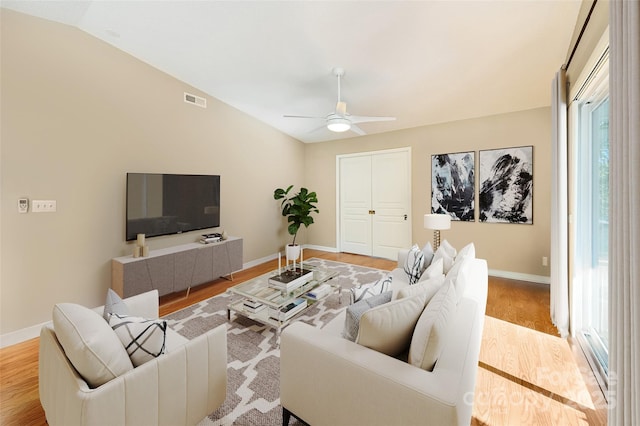 living area featuring vaulted ceiling, wood finished floors, visible vents, and baseboards