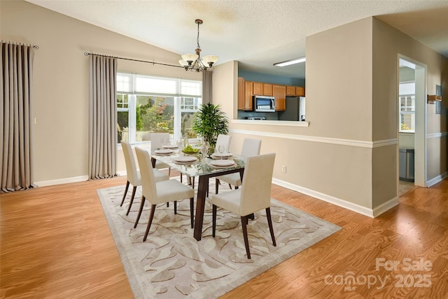 dining area featuring light wood-style floors, baseboards, a chandelier, and a textured ceiling