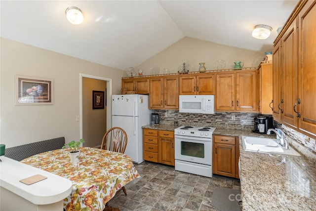 kitchen featuring lofted ceiling, sink, light stone counters, and white appliances