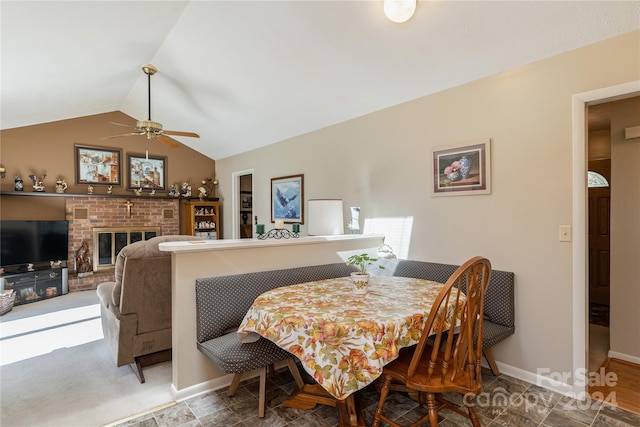 dining room with vaulted ceiling, a brick fireplace, and ceiling fan