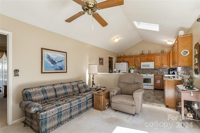 carpeted living room featuring lofted ceiling with skylight, sink, and ceiling fan