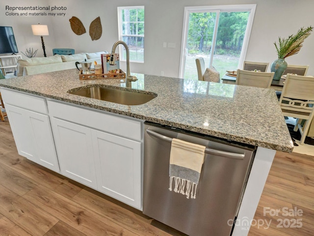 kitchen with a kitchen island with sink, dishwasher, white cabinets, light hardwood / wood-style flooring, and sink