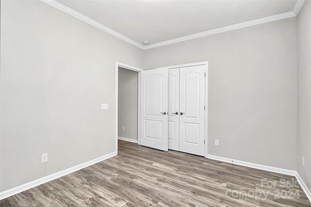 unfurnished bedroom with ornamental molding, wood-type flooring, and a closet