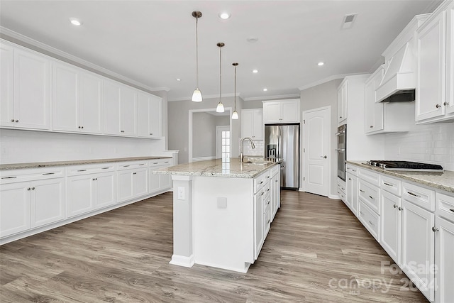 kitchen with appliances with stainless steel finishes, an island with sink, white cabinetry, and light hardwood / wood-style floors