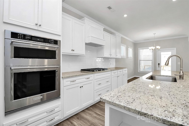 kitchen featuring light stone countertops, appliances with stainless steel finishes, sink, white cabinets, and ornamental molding