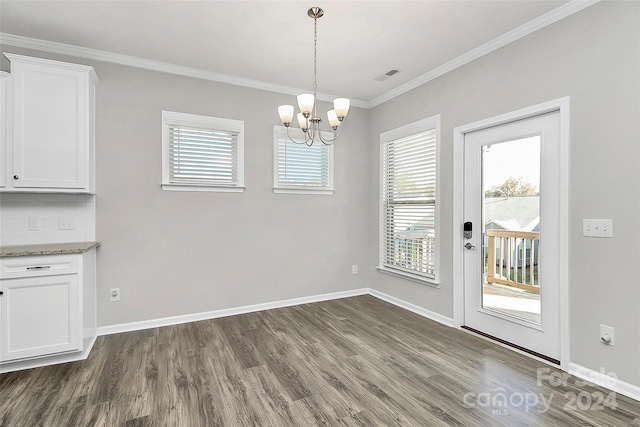 unfurnished dining area featuring an inviting chandelier, crown molding, and dark hardwood / wood-style floors