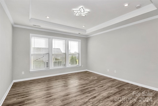 spare room featuring crown molding, a tray ceiling, and dark hardwood / wood-style flooring