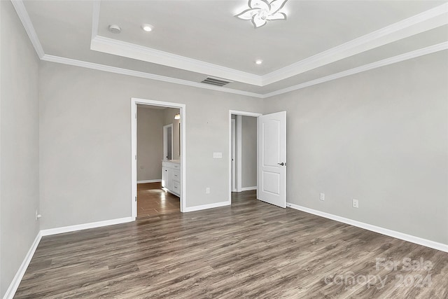 unfurnished bedroom featuring a tray ceiling, ornamental molding, and dark hardwood / wood-style flooring