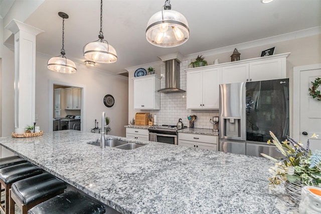 kitchen with white cabinetry, sink, washing machine and dryer, wall chimney exhaust hood, and stainless steel appliances