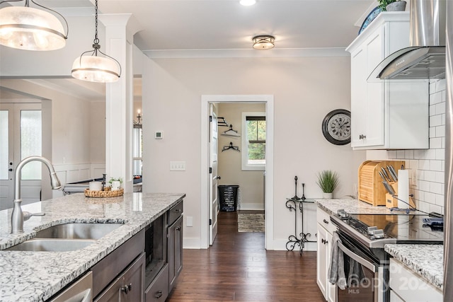 kitchen featuring wall chimney exhaust hood, white cabinetry, sink, and light stone counters