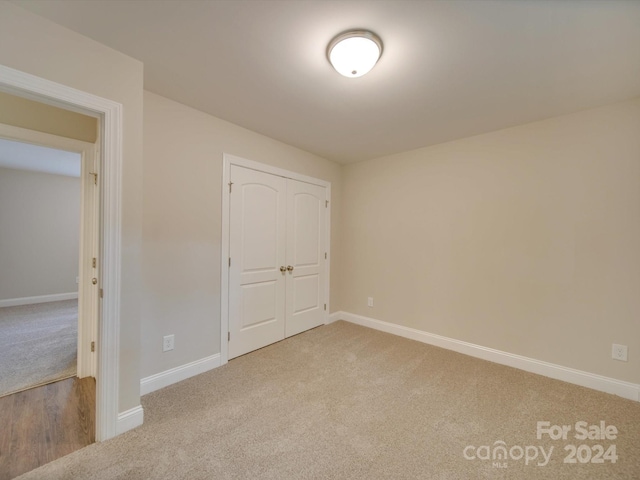 unfurnished bedroom with a closet and light colored carpet