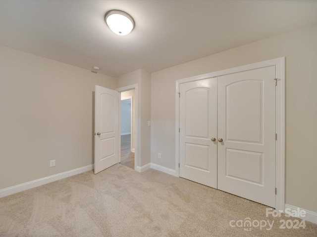 unfurnished bedroom featuring light carpet and a closet