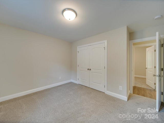 unfurnished bedroom featuring a closet and light carpet