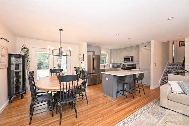 dining room featuring sink, a chandelier, and light wood-type flooring