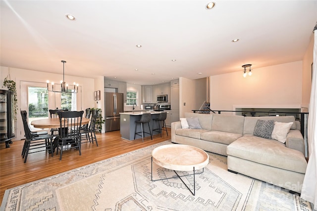 living room with light hardwood / wood-style floors, an inviting chandelier, and sink