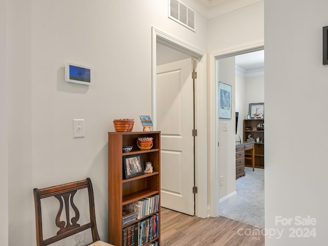 corridor with ornamental molding and light wood-type flooring