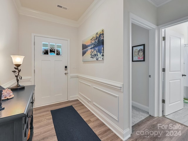 entryway featuring ornamental molding and light hardwood / wood-style flooring