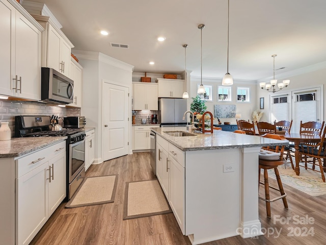 kitchen featuring white cabinetry, stainless steel appliances, a center island with sink, and sink