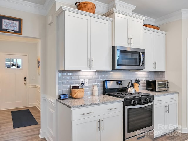 kitchen featuring decorative backsplash, white cabinets, light stone counters, light hardwood / wood-style flooring, and stainless steel appliances