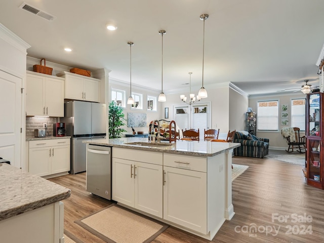 kitchen featuring sink, a kitchen island with sink, decorative light fixtures, and light hardwood / wood-style floors