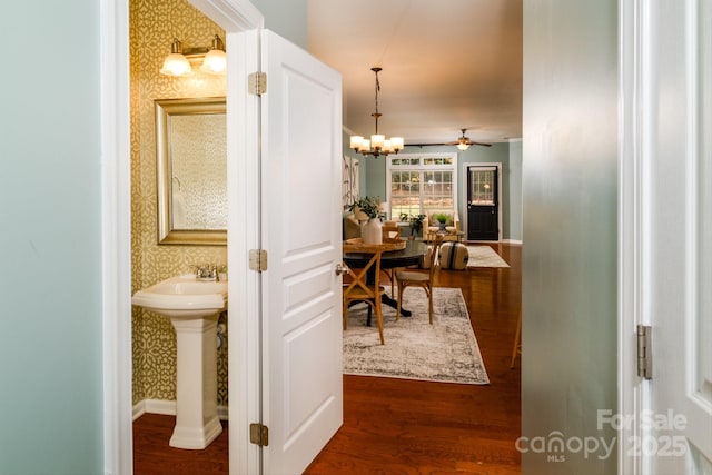 corridor with a notable chandelier, sink, and dark wood-type flooring