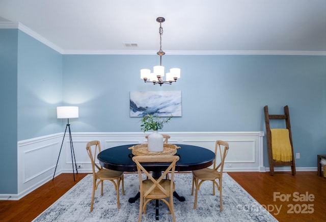 dining space featuring dark hardwood / wood-style flooring, crown molding, and an inviting chandelier