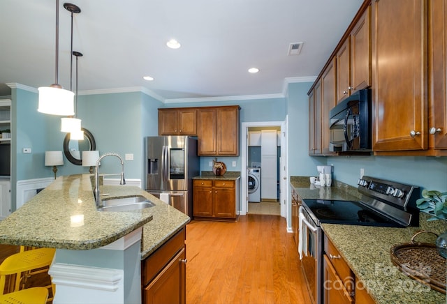 kitchen featuring sink, stainless steel appliances, a kitchen breakfast bar, washer / clothes dryer, and crown molding