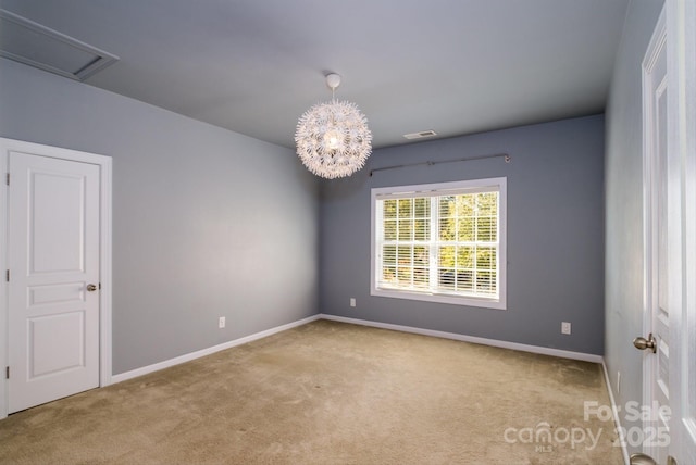 spare room with light carpet and a chandelier