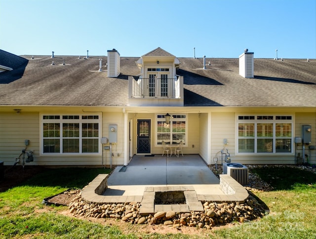 rear view of house with cooling unit, a balcony, a patio, and an outdoor fire pit