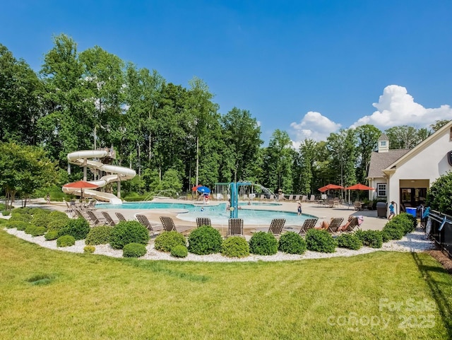 view of swimming pool with a patio, a lawn, and a water slide