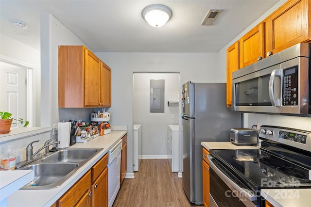 kitchen featuring electric panel, appliances with stainless steel finishes, independent washer and dryer, light hardwood / wood-style flooring, and sink