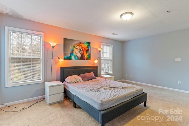 bedroom with light carpet and multiple windows