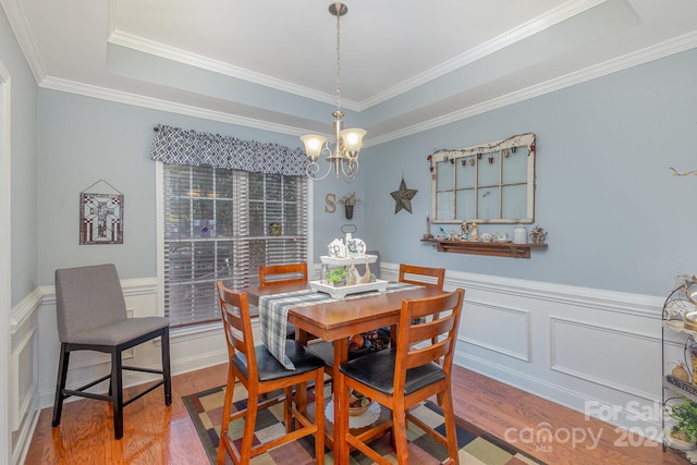 dining room with a raised ceiling, ornamental molding, an inviting chandelier, and hardwood / wood-style floors