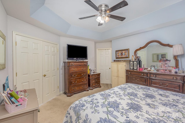 bedroom with a raised ceiling, light carpet, and ceiling fan