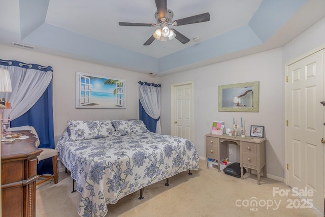 bedroom featuring light colored carpet, ceiling fan, and a tray ceiling