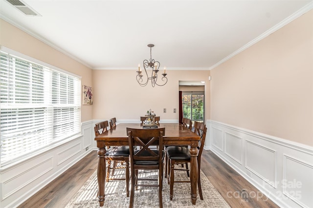 dining area featuring an inviting chandelier, ornamental molding, and dark hardwood / wood-style flooring