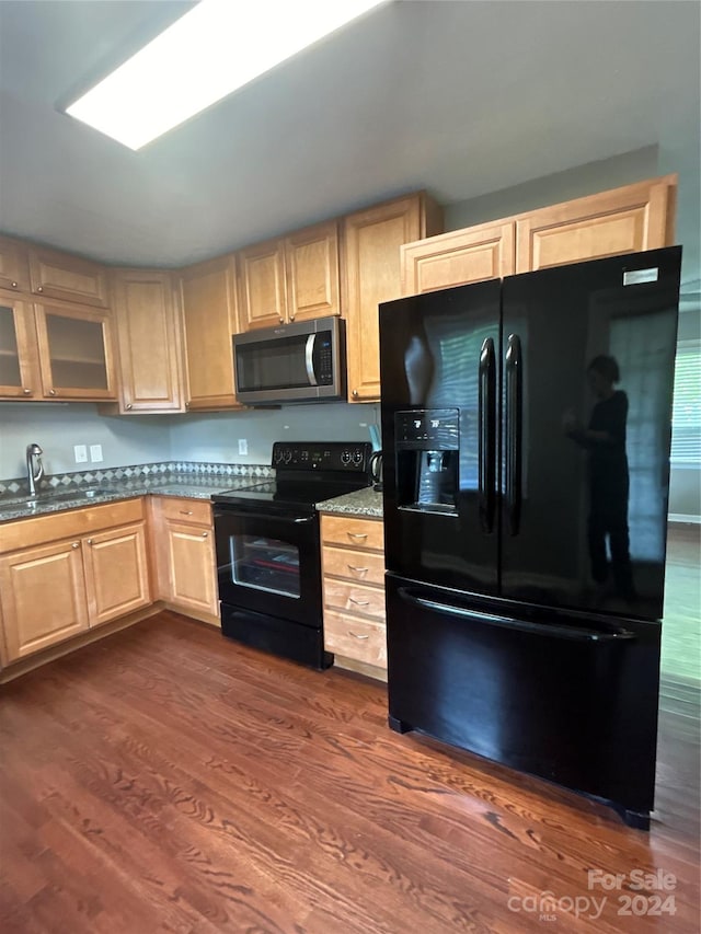 kitchen featuring black appliances, sink, dark stone counters, dark wood-type flooring, and light brown cabinets