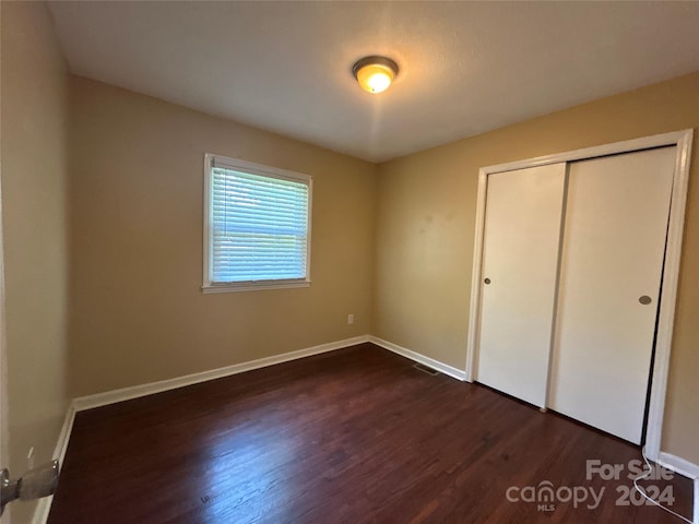 unfurnished bedroom featuring a closet and dark hardwood / wood-style floors