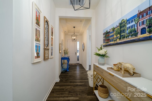 hall with dark wood-type flooring and an inviting chandelier