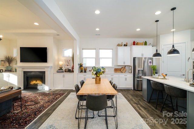 kitchen featuring decorative light fixtures, dark hardwood / wood-style flooring, a kitchen breakfast bar, white cabinets, and stainless steel fridge